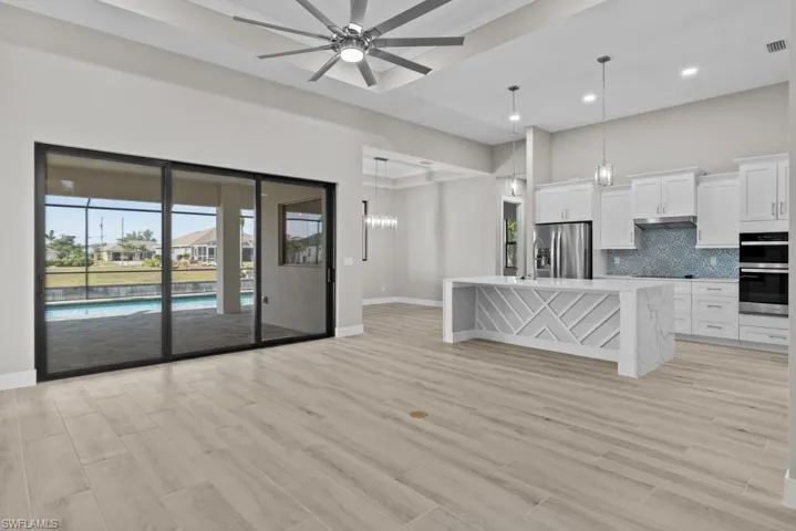 Unfurnished living room with baseboards, ceiling fan, light wood-style floors, recessed lighting, and a chandelier