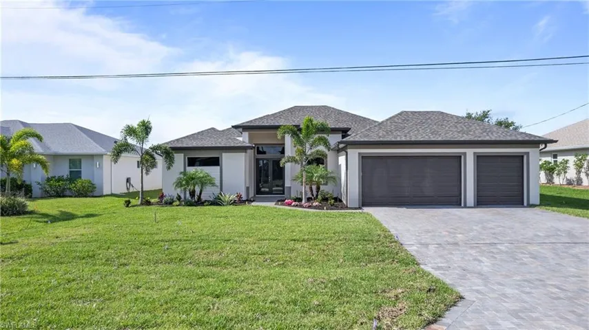 Prairie-style home with decorative driveway, a garage, a front yard, and stucco siding