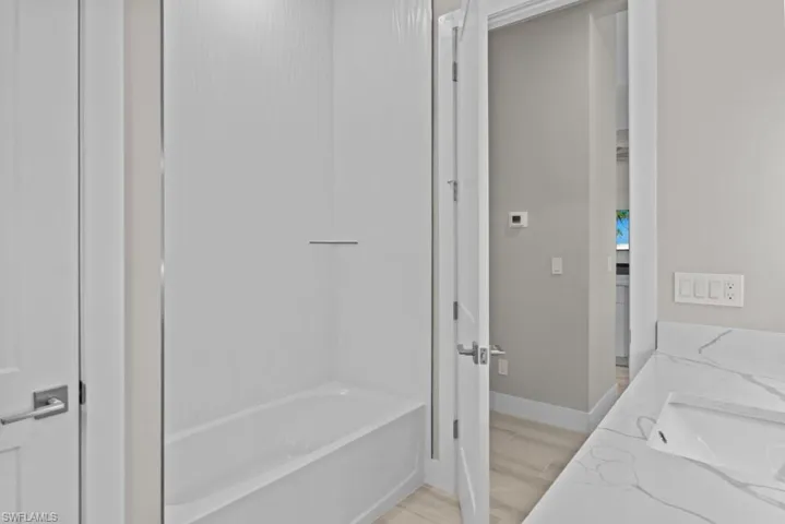 2nd Bathroom with a sink, baseboards, washtub / shower combination, and wood finished floors
