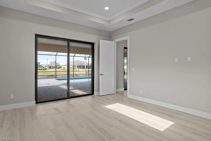 Masterbed room with crown molding, light wood finished floors, baseboards, recessed lighting, and a tray ceiling