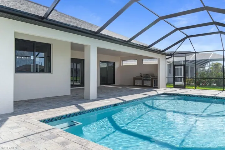 Swimming pool with area for grilling, a patio area, and glass enclosure