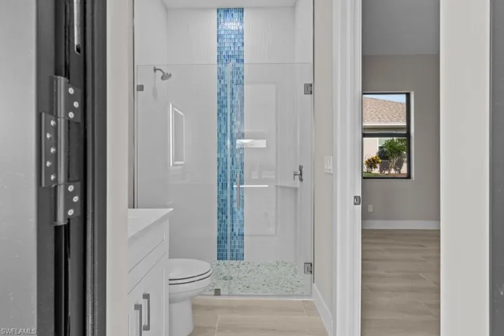Pool Bathroom featuring a shower stall, toilet, wood finished floors, and vanity