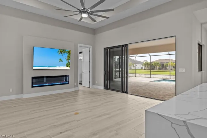 Living area with ceiling fan, light wood-type flooring, a glass covered fireplace, and baseboards