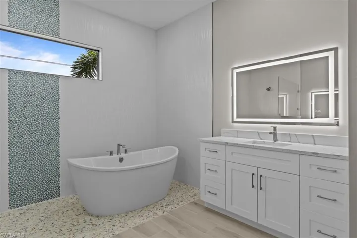 Bathroom with vanity, a soaking tub, and wood finished floors