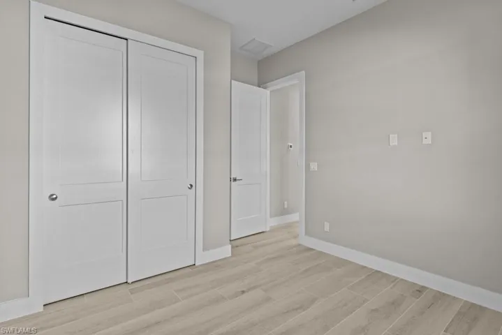 bedroom with light wood-style flooring, baseboards, and a closet