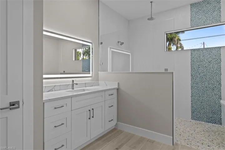 Full bathroom featuring walk in shower, vanity, wood finished floors, and baseboards