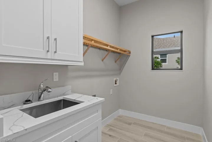 Laundry room featuring hookup for a washing machine, cabinet space, baseboards, and light wood-style flooring