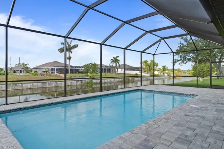 Swimming pool with a water view, a residential view, a patio, and glass enclosure