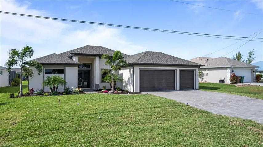 View of front of property with stucco siding, a front yard, an attached garage, decorative driveway, and french doors
