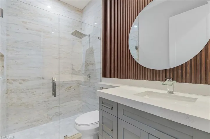 Full bathroom with wallpapered walls, vanity, and a marble finish shower