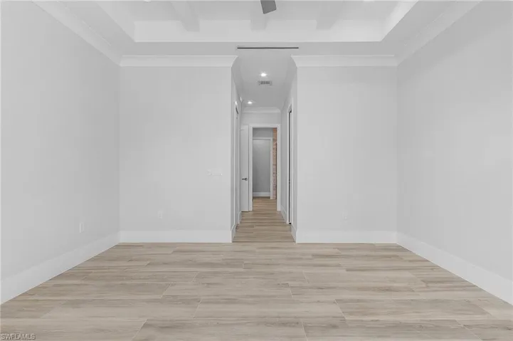 Empty room with ornamental molding, recessed lighting, wood tiled floors, and beamed ceiling