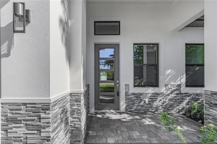 Property entrance with stone siding, a patio, and stucco siding