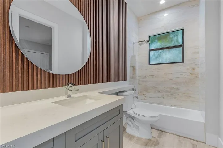 Full bathroom with wallpapered walls, vanity, and shower / tub combination