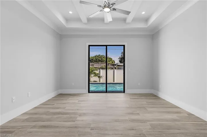 Empty room featuring light wood-style flooring, a ceiling fan, coffered ceiling, and recessed lighting