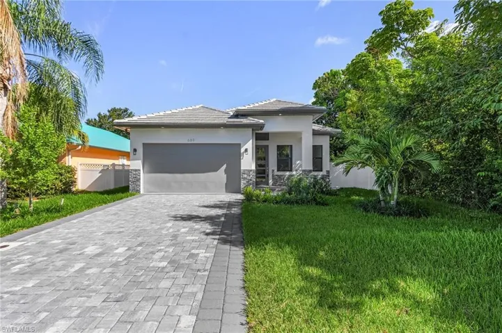 Prairie-style house with decorative driveway, an attached garage, stucco siding, stone siding, and a tile roof