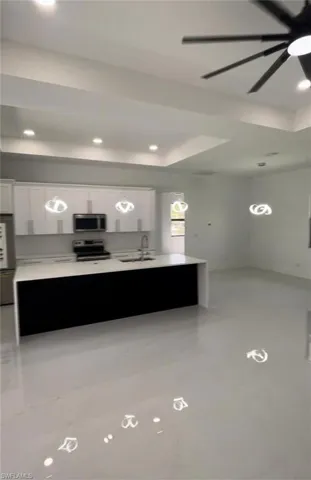 Kitchen featuring appliances with stainless steel finishes, sink, white cabinets, a tray ceiling, and ceiling fan