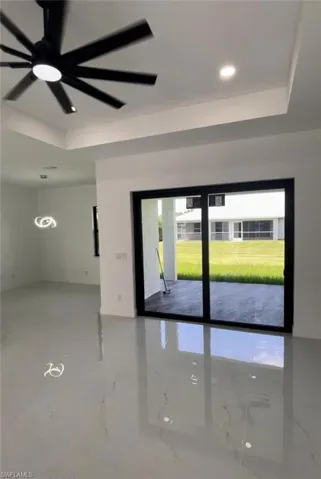 Unfurnished room featuring ceiling fan, concrete floors, and a tray ceiling