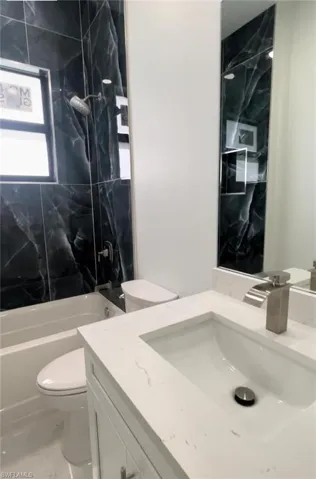 Full bathroom with tiled shower / bath, toilet, and vanity