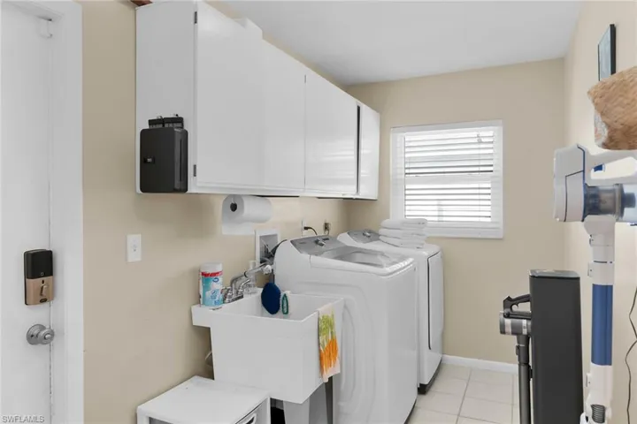Laundry room featuring cabinet space, separate washer and dryer, and light tile patterned floors