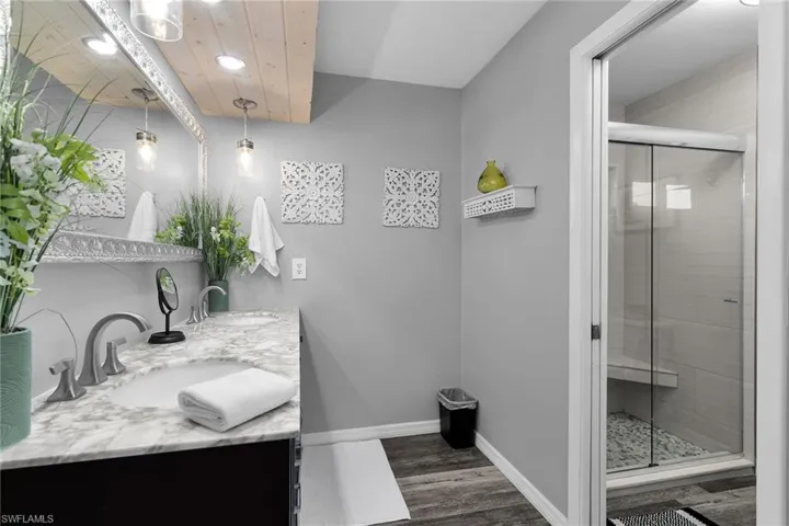 Bathroom with double vanity, a stall shower, dark wood-type flooring, and recessed lighting