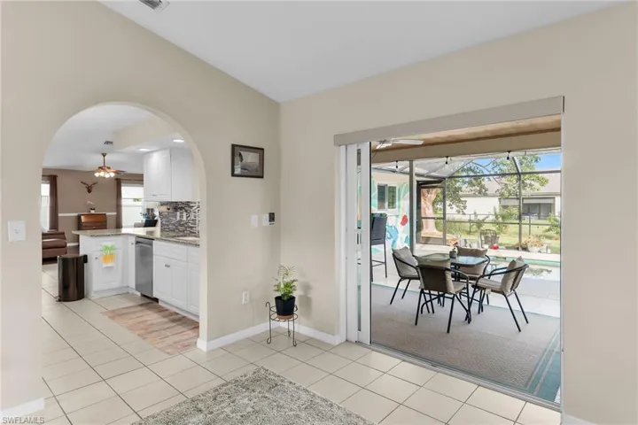 Dining space with ceiling fan, a sunroom, vaulted ceiling, light tile patterned flooring, and arched walkways