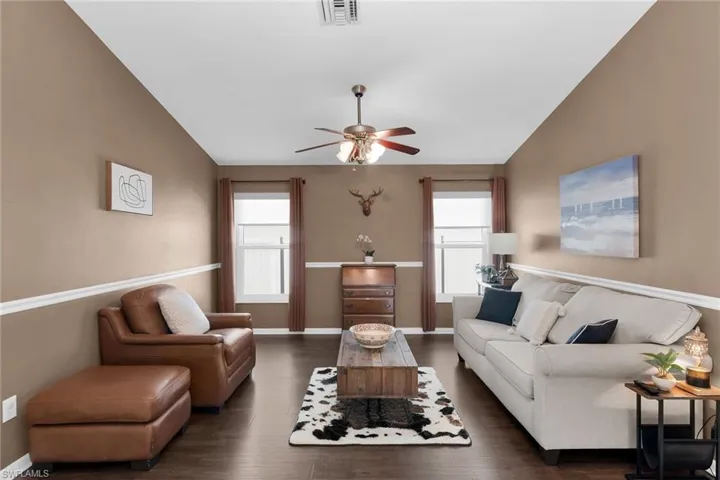 Living room featuring vaulted ceiling, a ceiling fan, and wood finished floors