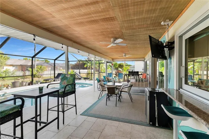 Sunroom featuring outdoor dining space, ceiling fan, a patio area, and a residential view