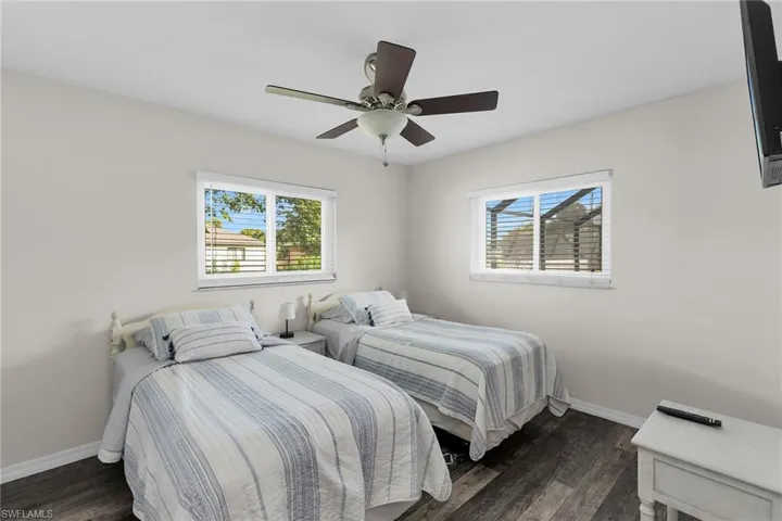 Bedroom with dark wood-type flooring, multiple windows, and a ceiling fan