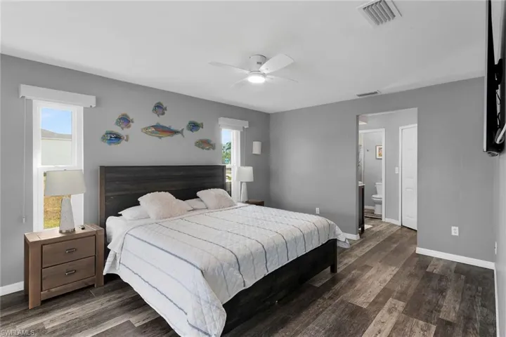 Bedroom featuring dark wood-style floors, a ceiling fan, and ensuite bath
