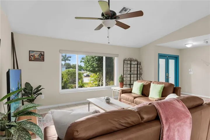 Living room featuring a ceiling fan, french doors, vaulted ceiling, and tile patterned flooring