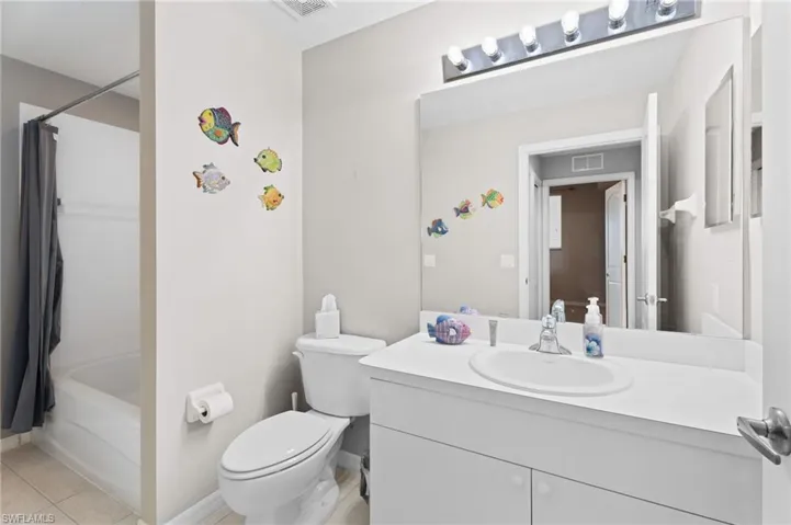 patterned floors, shower / bathtub combination with curtain, vanity, and toilet