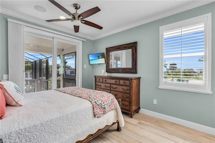 Bedroom featuring light hardwood / wood-style floors, multiple windows, access to exterior, and ceiling fan.  virtually enhanced photo