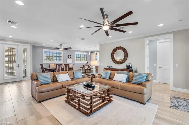 Living room featuring light hardwood / wood-style flooring, ceiling fan, and ornamental molding /  virtually enhanced photo