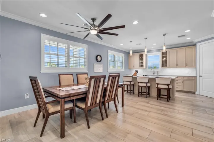 Dining space featuring ceiling fan, ornamental molding, and light hardwood / wood-style floors /  virtually enhanced photo