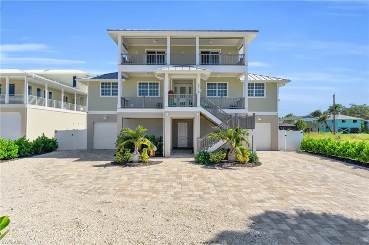Coastal home featuring a balcony, a garage, and covered porch VIRTUALLY ENHANCED