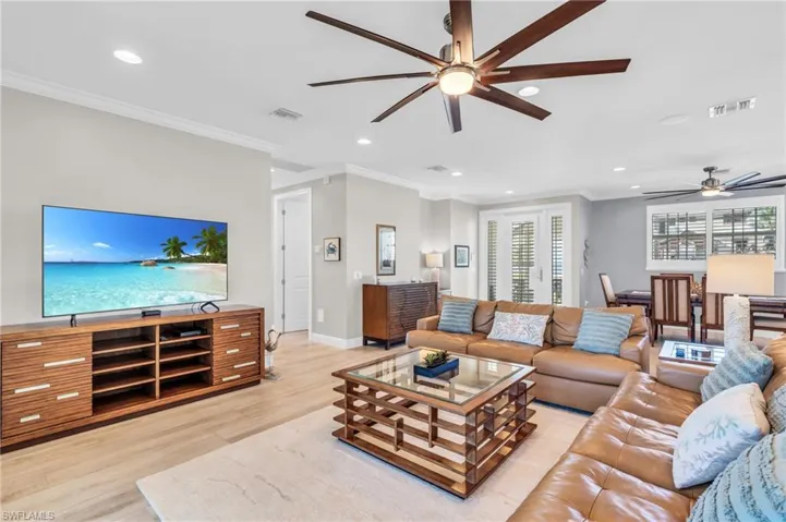 Living room featuring ceiling fan, crown molding, and light hardwood / wood-style floors /  virtually enhanced photo