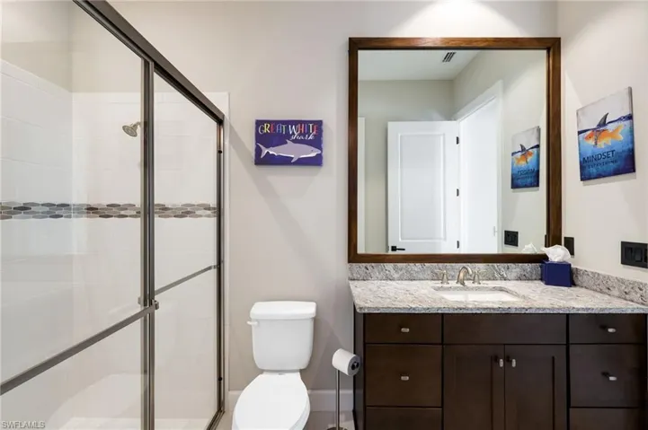 Bathroom featuring an enclosed shower, vanity, and toilet