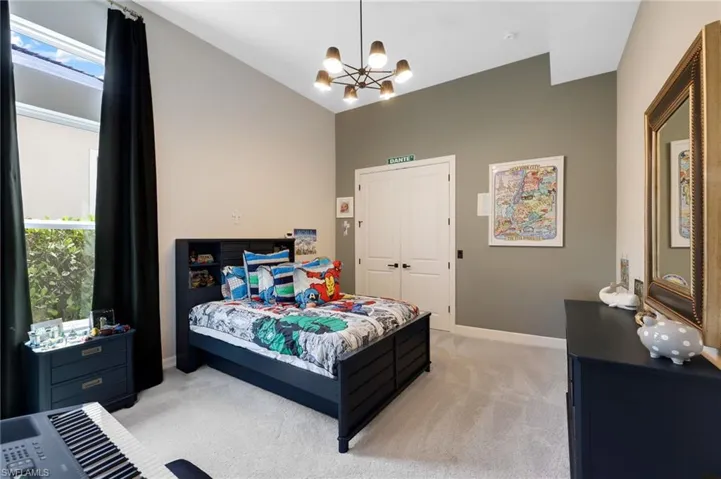 Carpeted bedroom featuring a closet, lofted ceiling, and an inviting chandelier