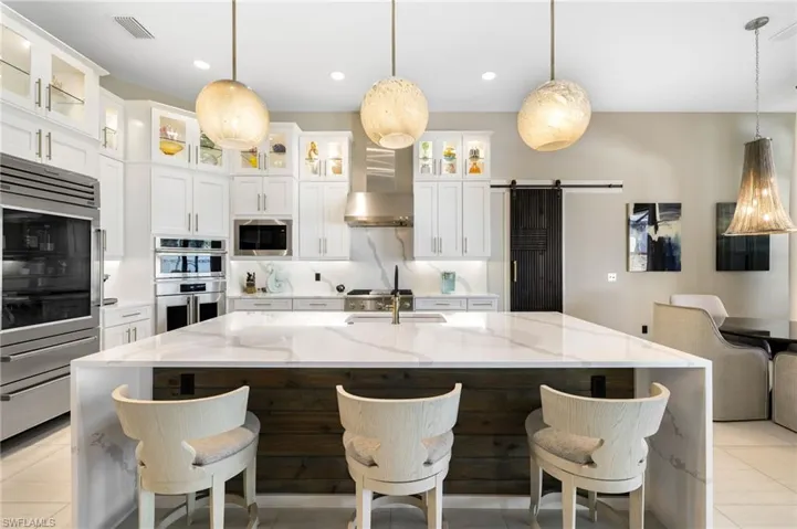 Kitchen with a large island, pendant lighting, a barn door, and light stone counters