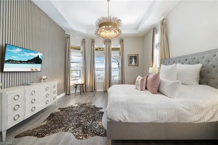 Bedroom featuring wood-type flooring, a chandelier, and a raised ceiling
