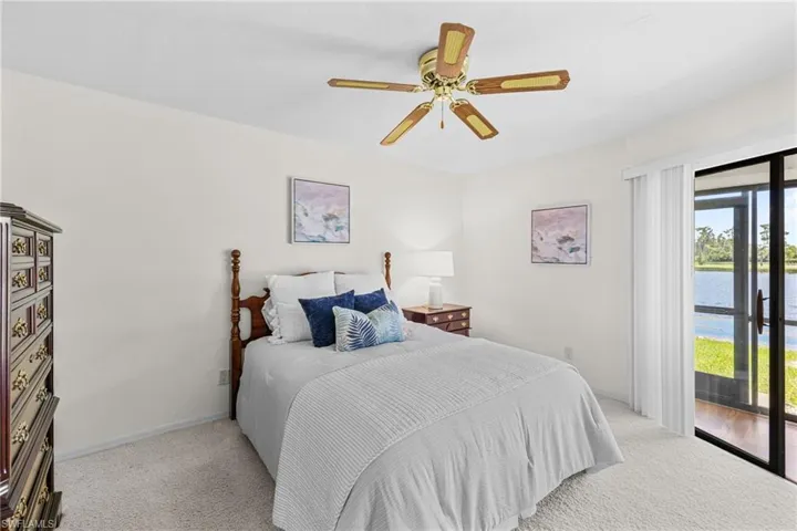 Carpeted bedroom featuring a water view, ceiling fan, and access to exterior
