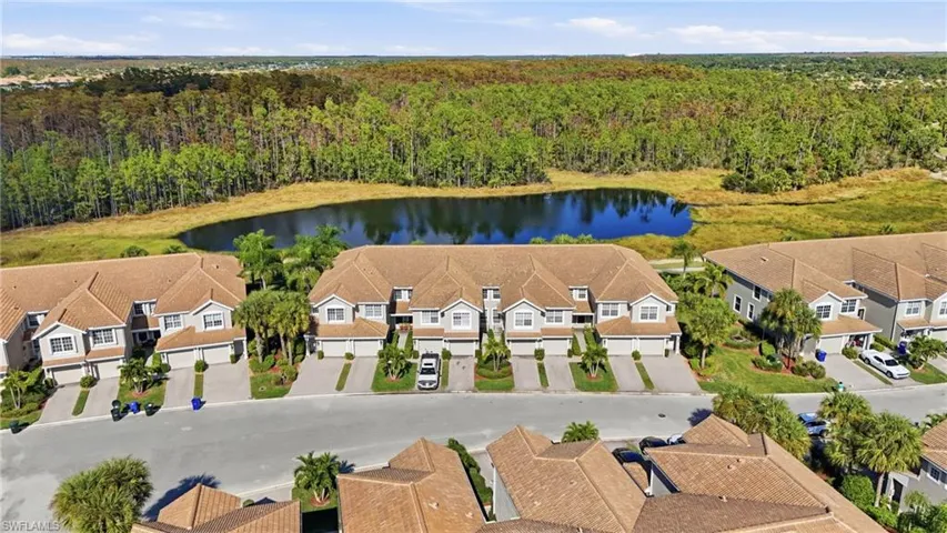 Aerial perspective of suburban area featuring a nearby body of water and a forest