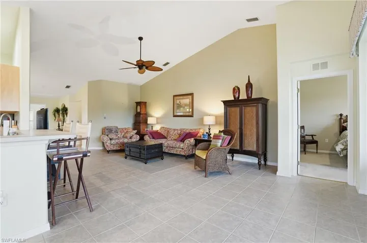 Living room featuring high vaulted ceiling, light tile patterned flooring, and ceiling fan
