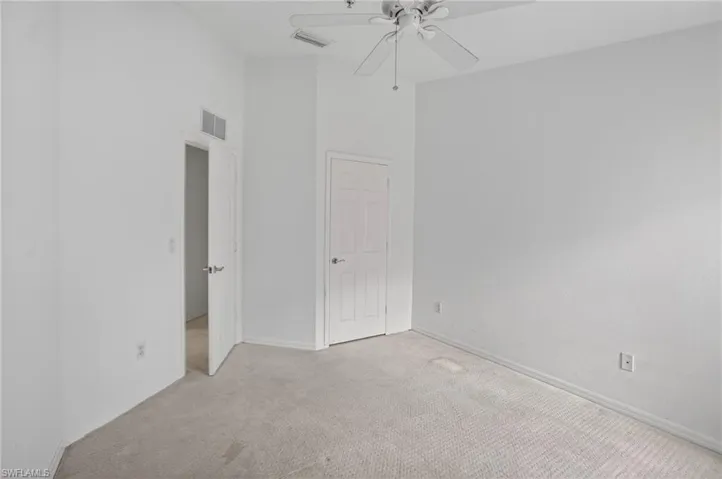 Carpeted interior space featuring white walls and a ceiling fan