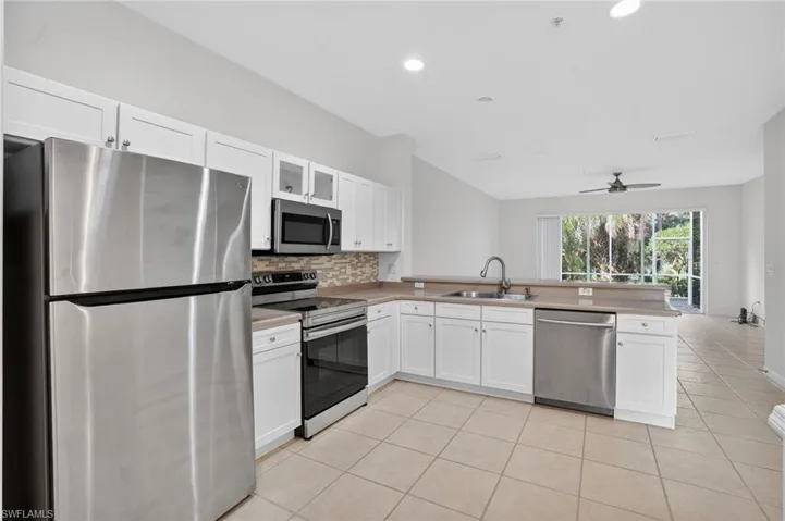 Kitchen featuring white cabinetry, stainless steel appliances, a breakfast bar, and tile flooring