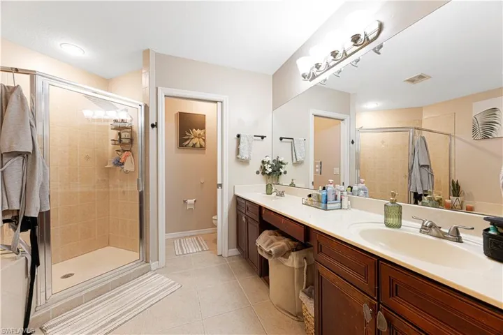 Bathroom with double vanity, a shower stall, and light tile patterned floors