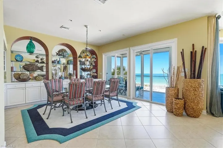 Formal dining area featuring tile flooring and an integrated built-in cabinet system with arched mirrored display shelving