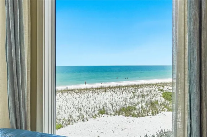 Expansive ocean vista through a large window, framed by drapes