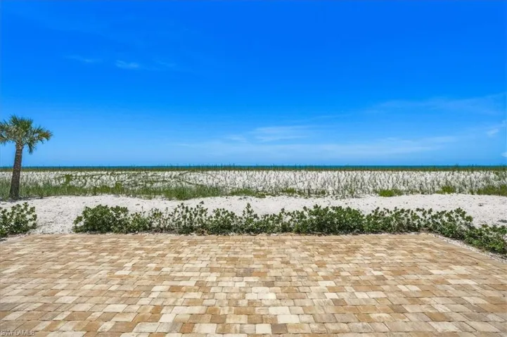 Paver patio offering direct access to the white sand beach and ocean beyond