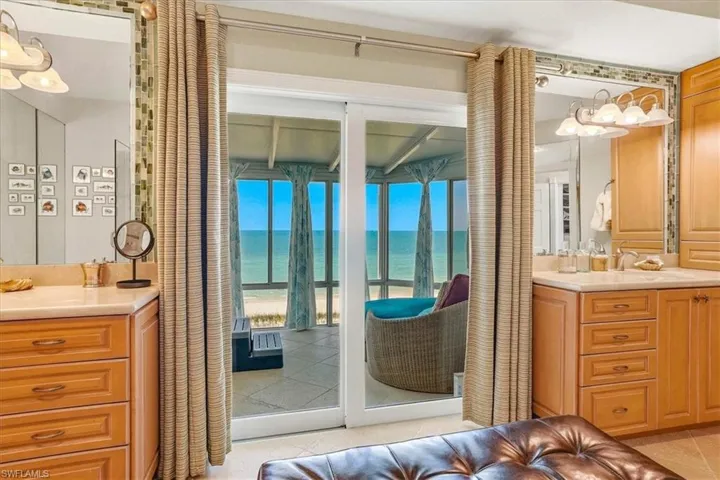 Sliding glass doors open to an enclosed sunroom overlooking the ocean